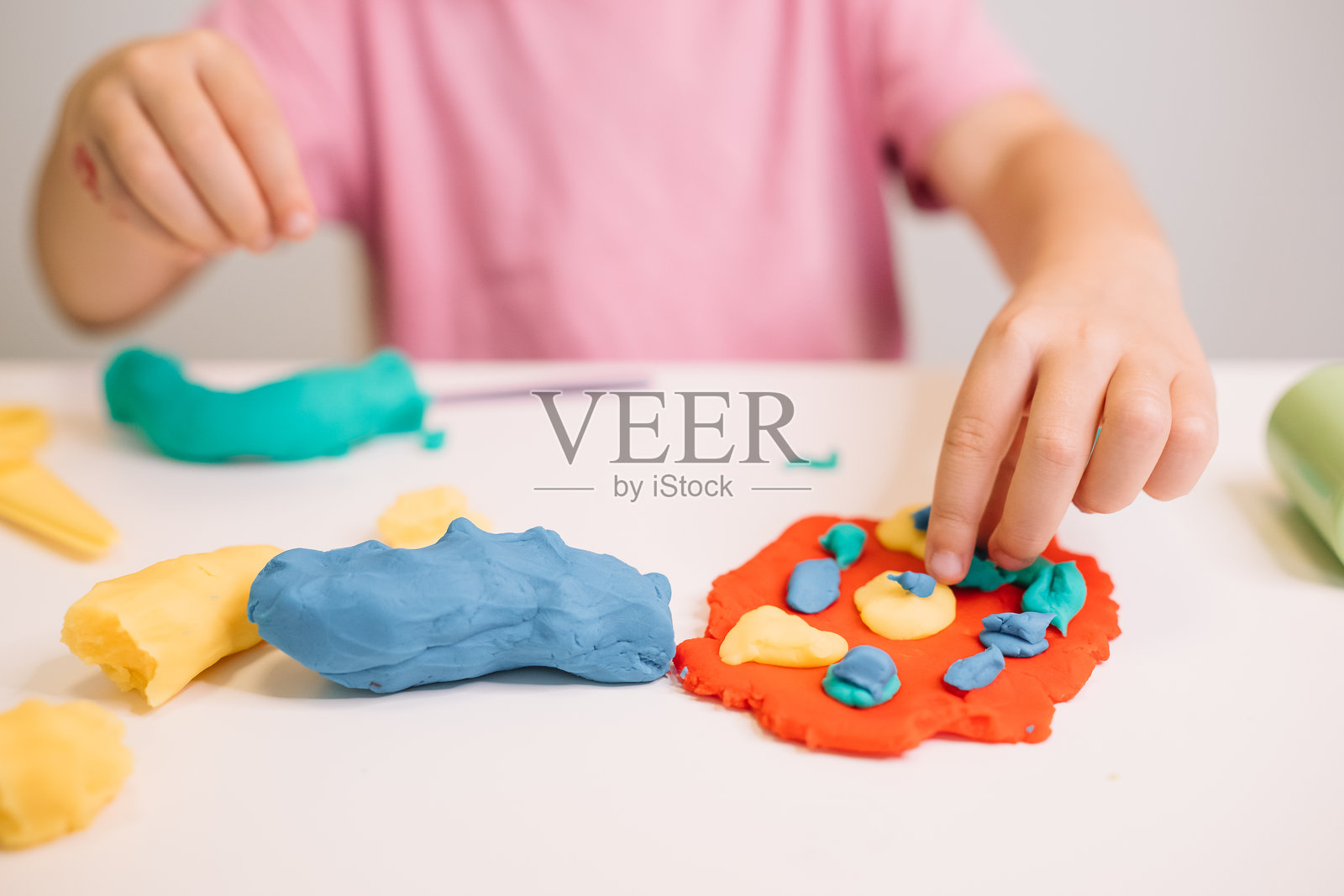 一个孩子在家中进行手工艺活动时，用彩色橡皮泥创造形状。照片摄影图片