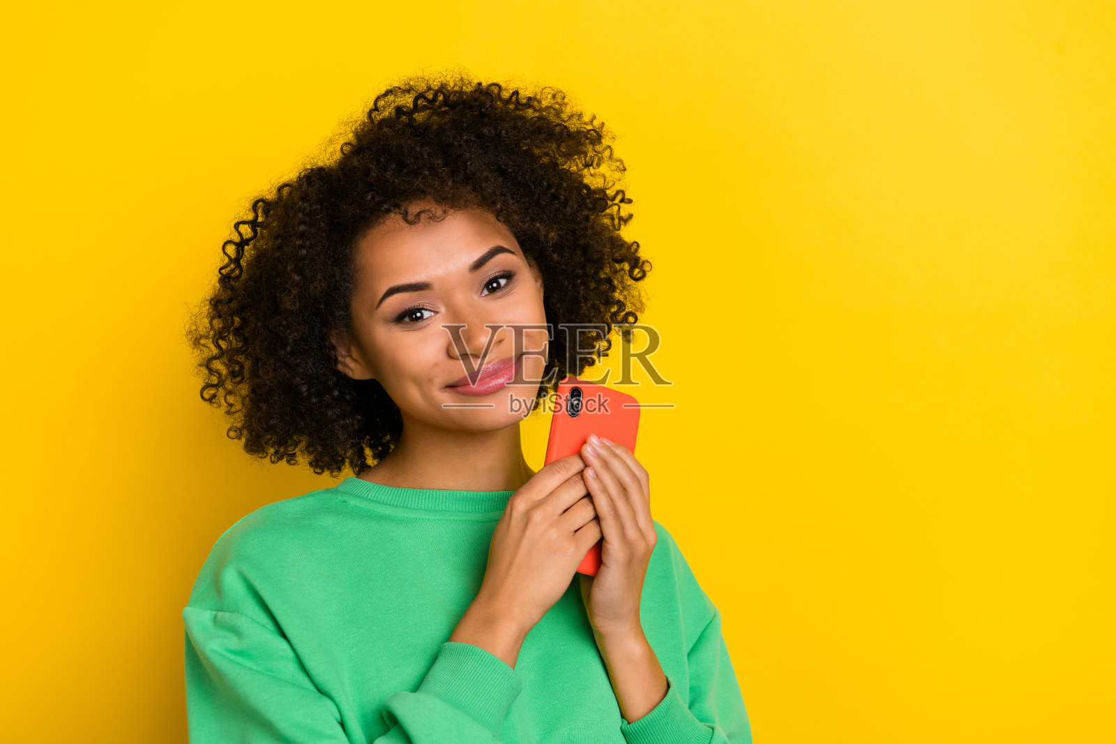 漂亮的人物肖像，手持电话设备，面向镜头，背景为黄色。照片摄影图片