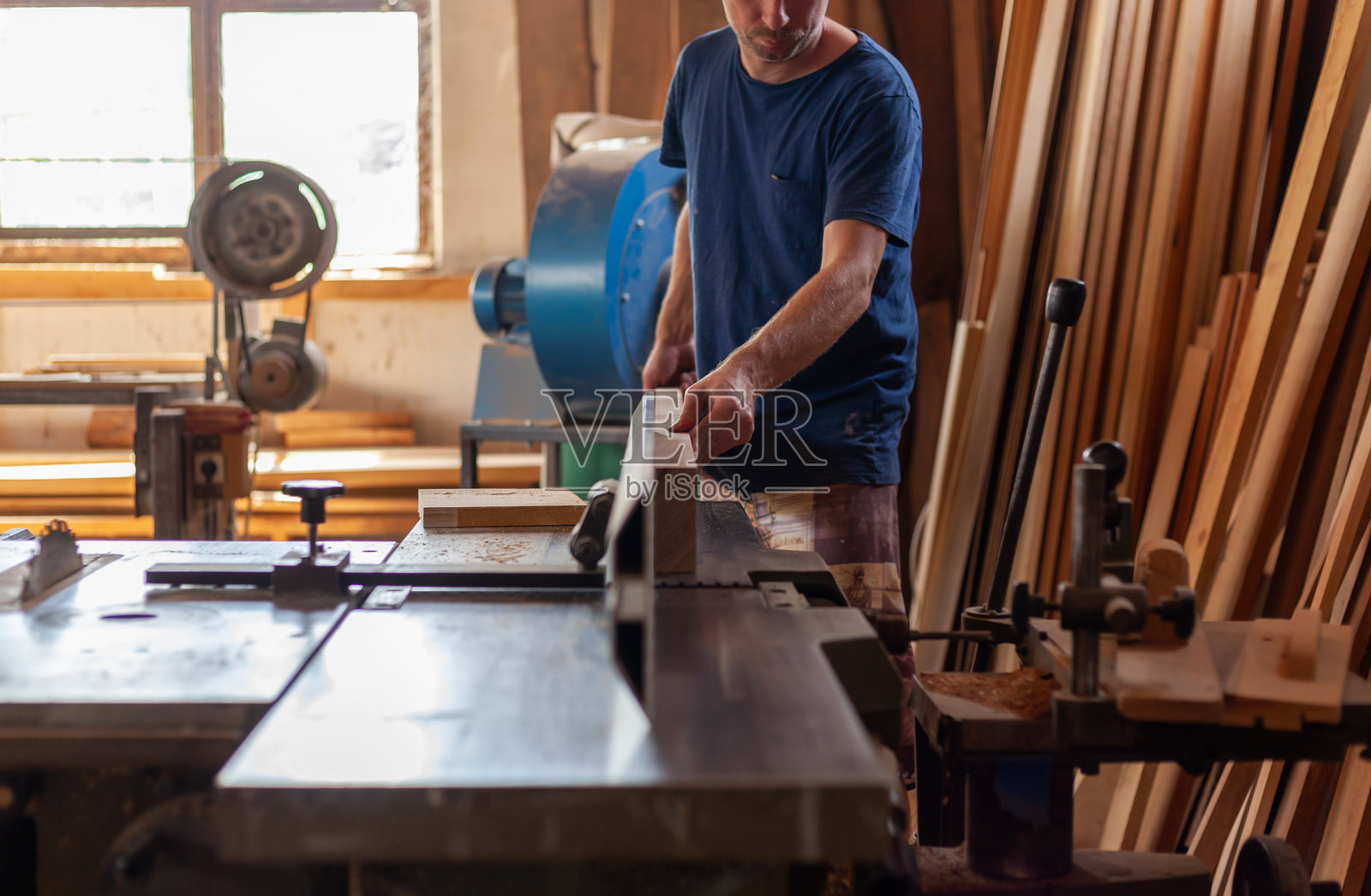 木工师傅双手引导木材在机器上操作照片摄影图片