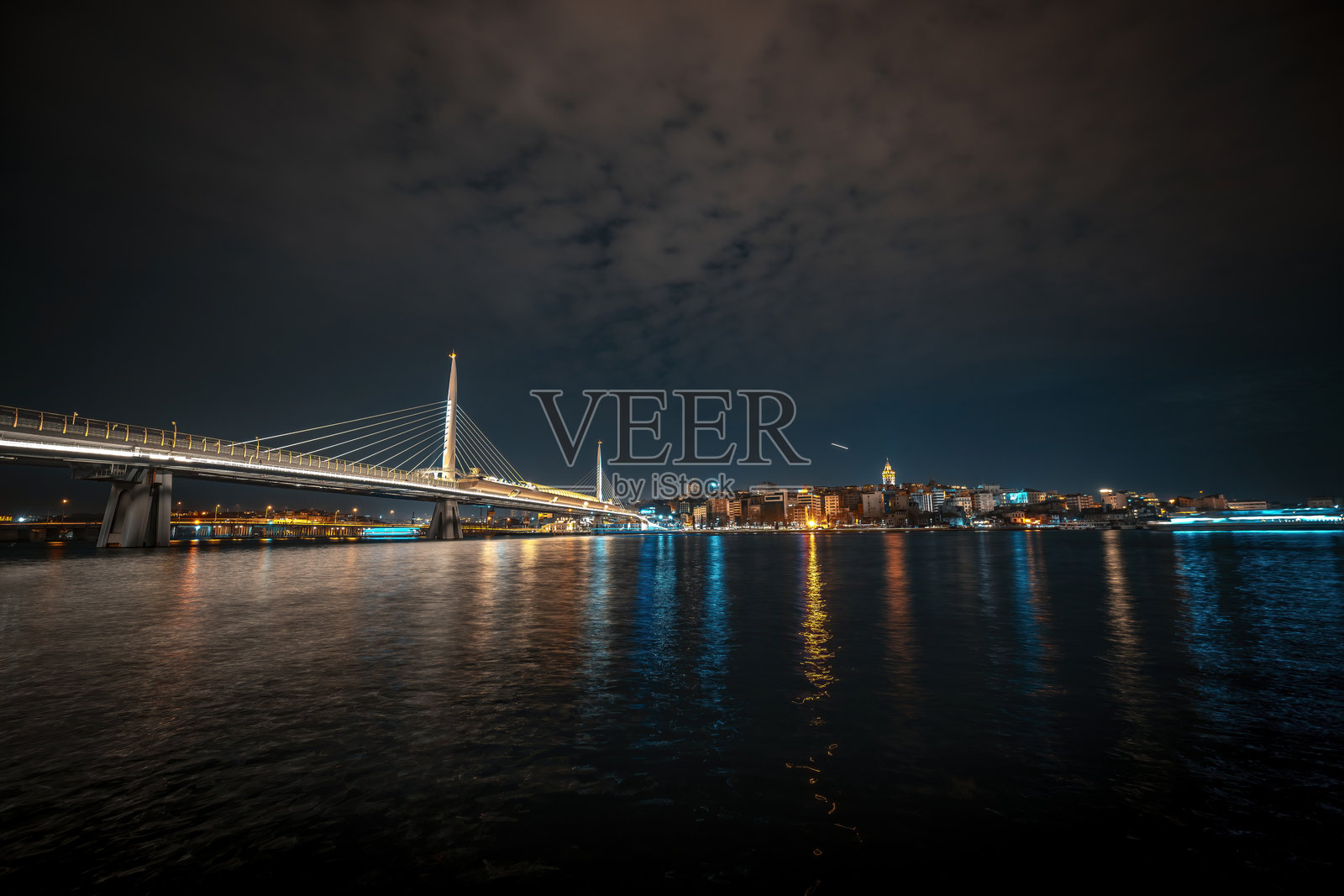 伊斯坦布尔，夜幕下海面上金角湾地铁桥的灯光与城市景观。照片摄影图片