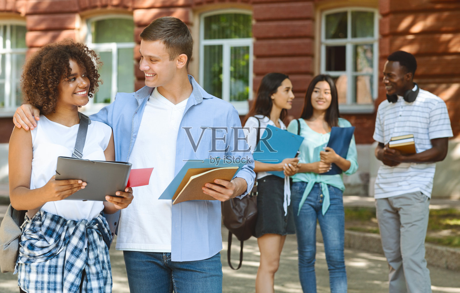 微笑的学生在课间户外拥抱他的黑人女友照片摄影图片