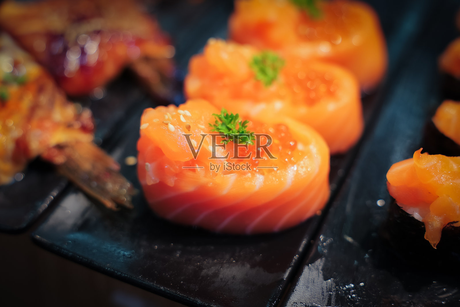 鲑鱼寿司上面淋有酱汁和美乃滋，整齐地摆放在托盘上，供顾客自取。照片摄影图片