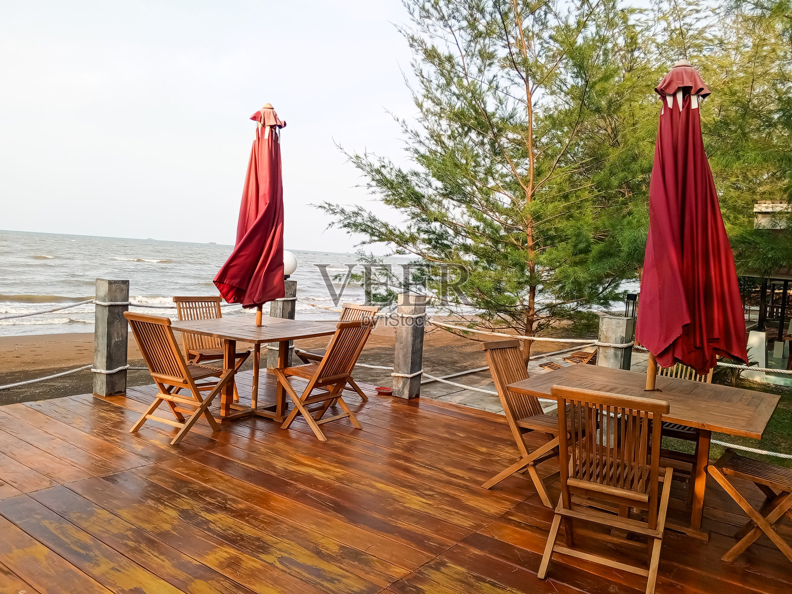 两套桌椅位于热带海滩边缘，配有红色伞。照片摄影图片