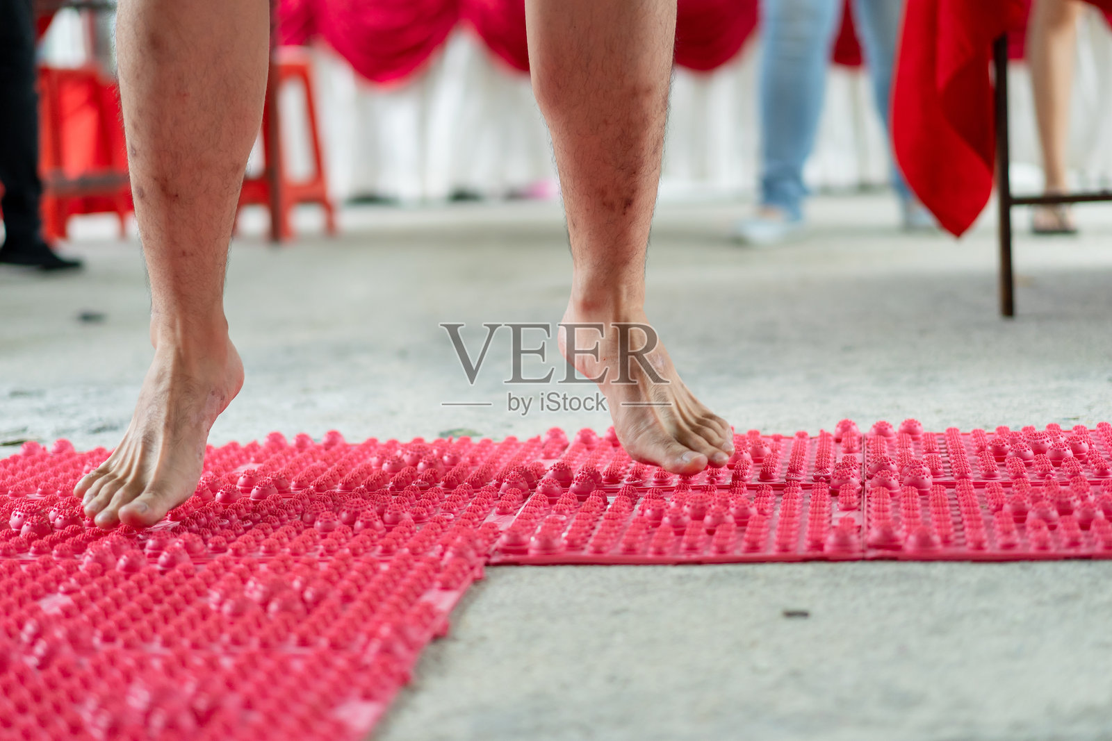 赤脚站在按摩垫上的男人。新郎闯关游戏。传统中国婚礼概念。照片摄影图片