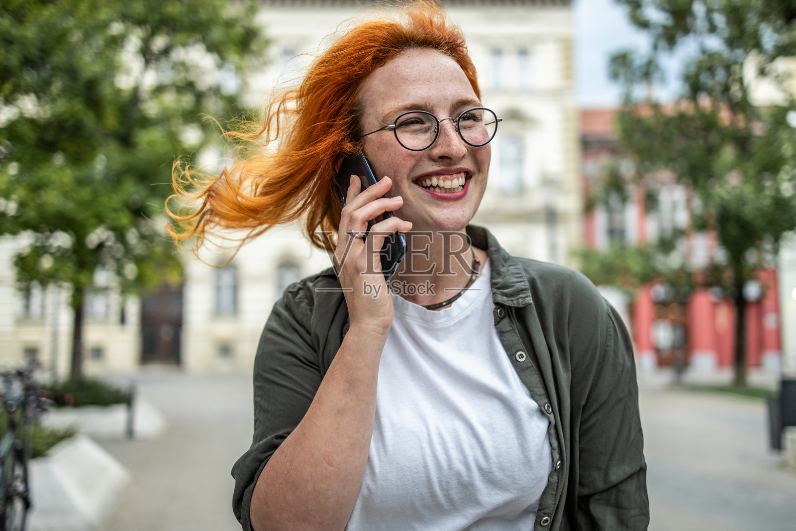 红发女孩在城市街道上通话，正在移动中照片摄影图片