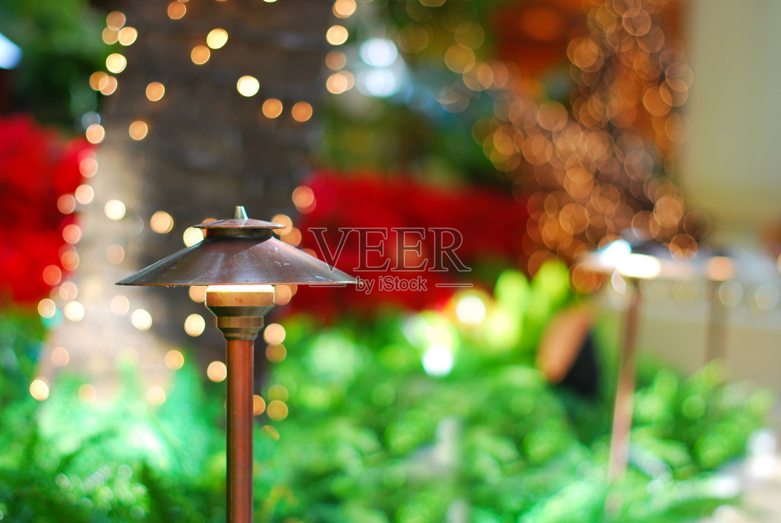 装饰性花园灯，背景为绿叶和红花的灯笼照片摄影图片