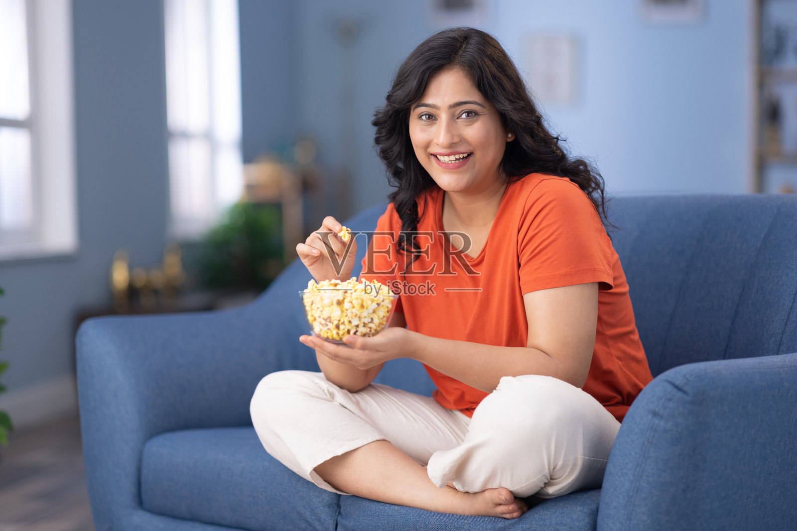 兴奋的成年女性手拿一碗爆米花观看电视照片摄影图片