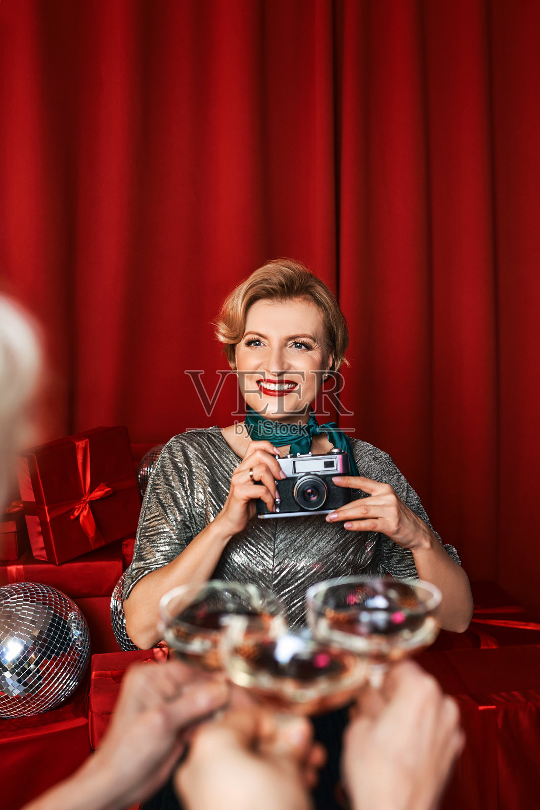 在红色帷幕背景下，快乐美丽的女摄影师在庆祝派对。职业，派对概念照片摄影图片