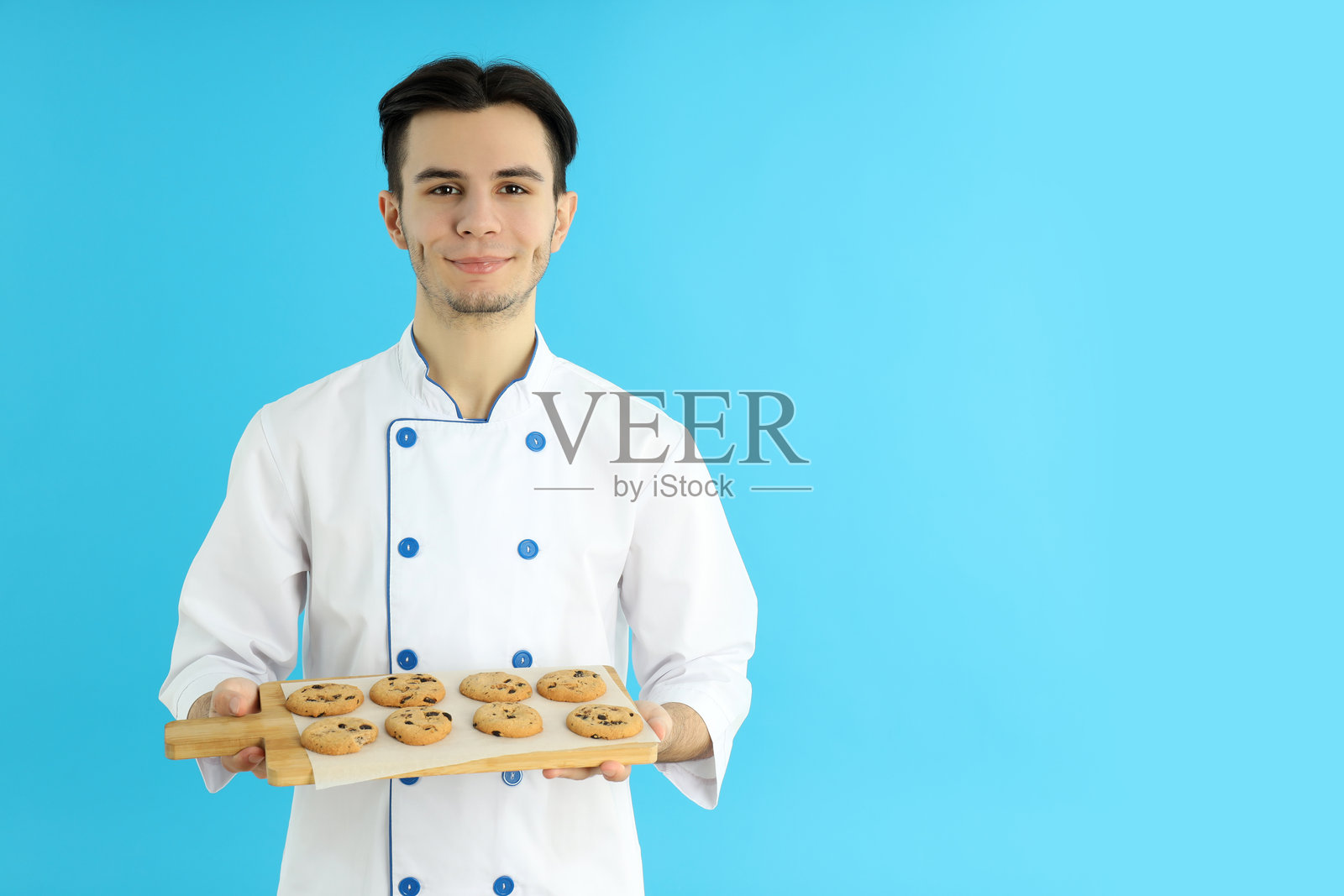 烹饪概念，年轻男性厨师在蓝色背景下照片摄影图片