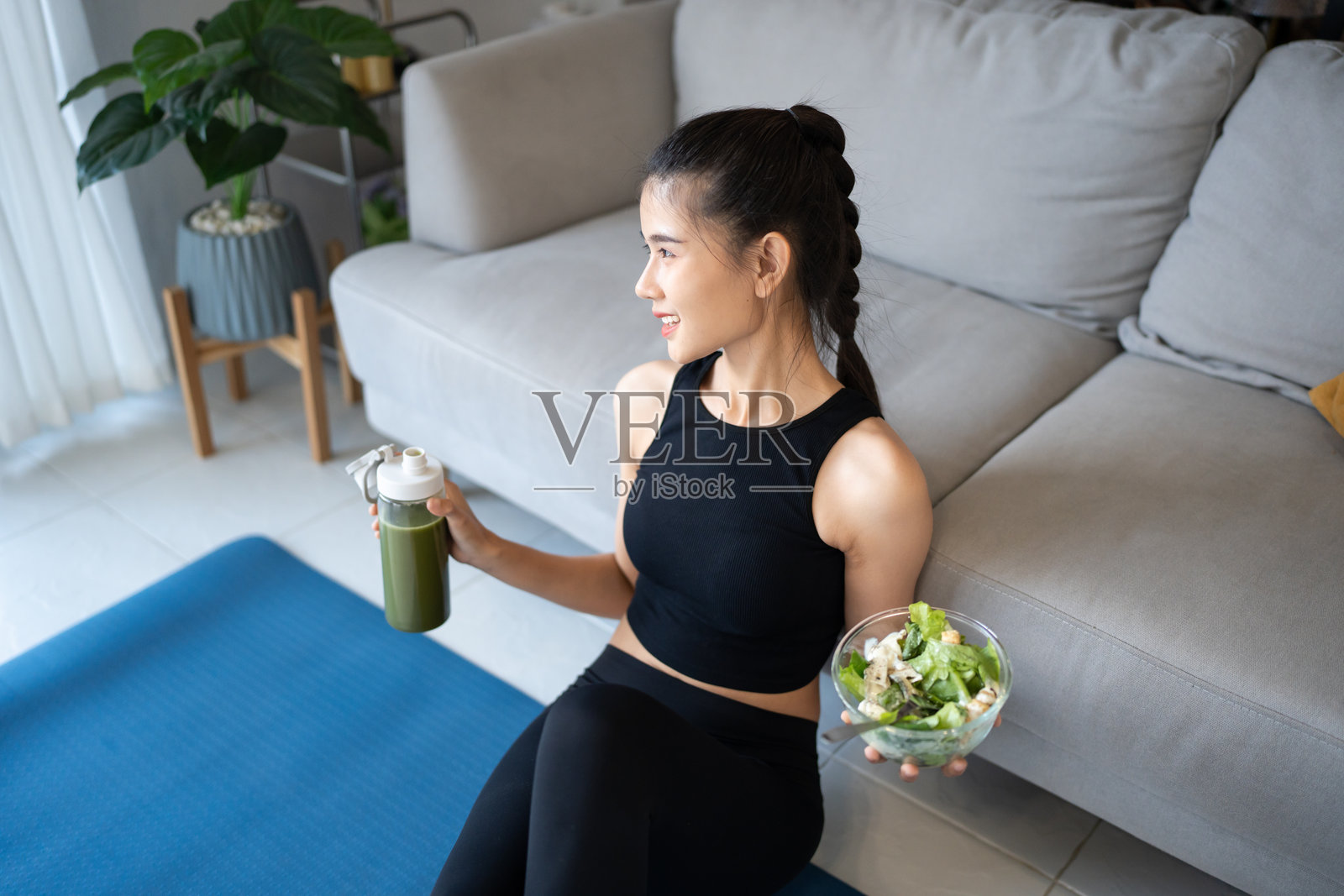 健身的亚洲女性在瑜伽馆享用健康沙拉，饮用有机绿色果昔，进行排毒饮食，锻炼后保持健康生活方式。照片摄影图片