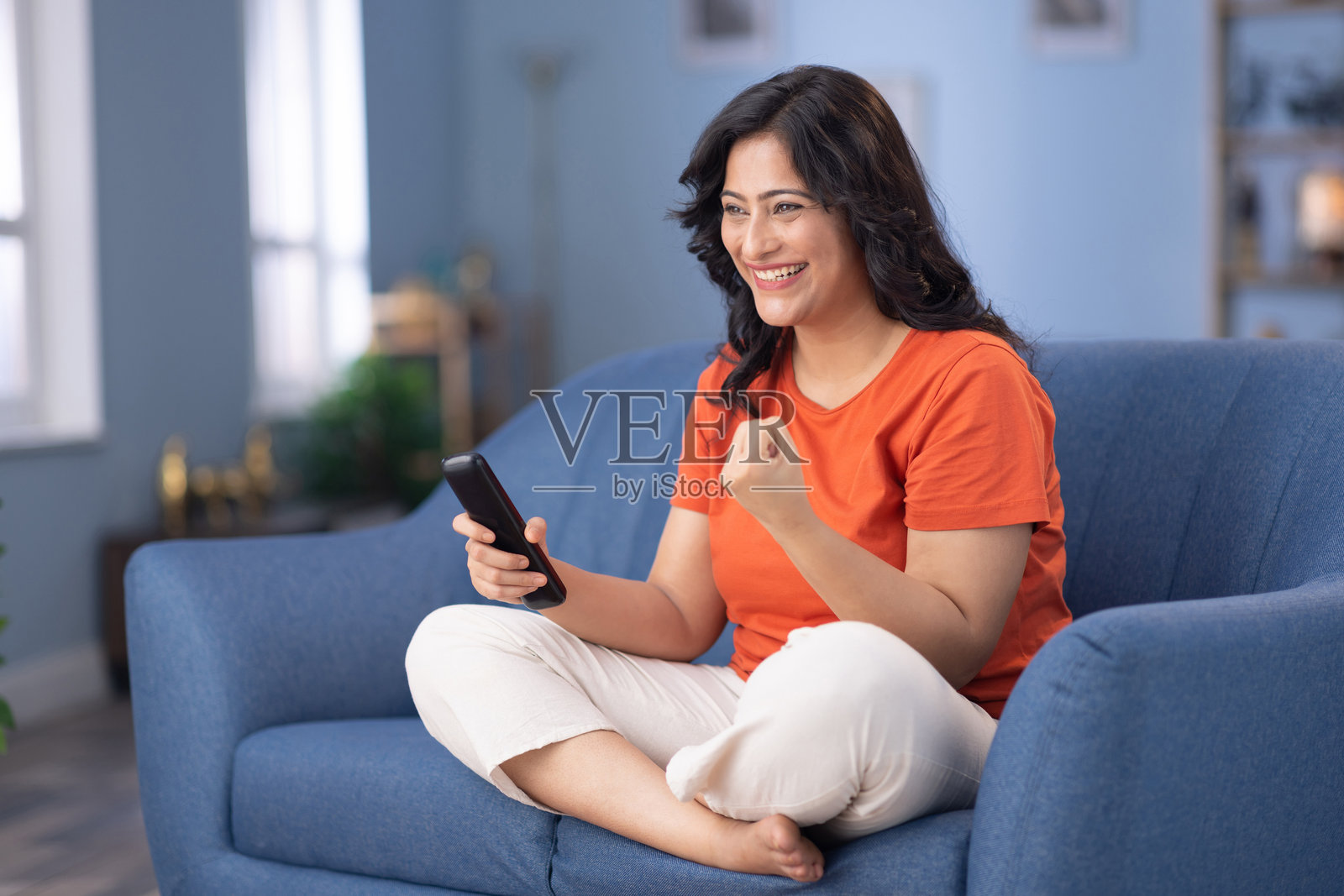 女人坐在家里的沙发上看电视的库存照片照片摄影图片