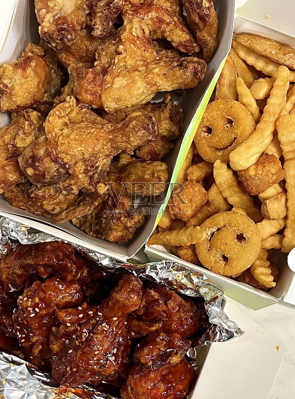 一盒带有特殊韩国调味料的韩国炸鸡。有些鸡块配有辣酱。外脆内嫩，美味可口。照片摄影图片