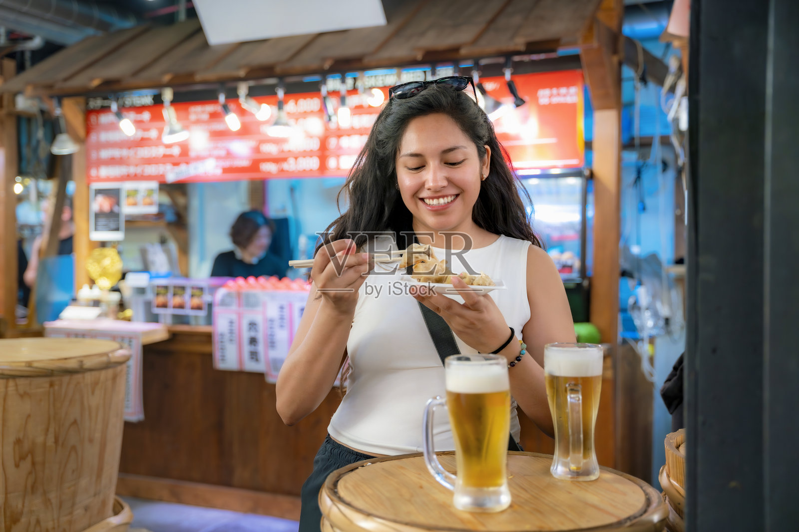 拉丁裔女性在京都市场享受街头美食和啤酒照片摄影图片