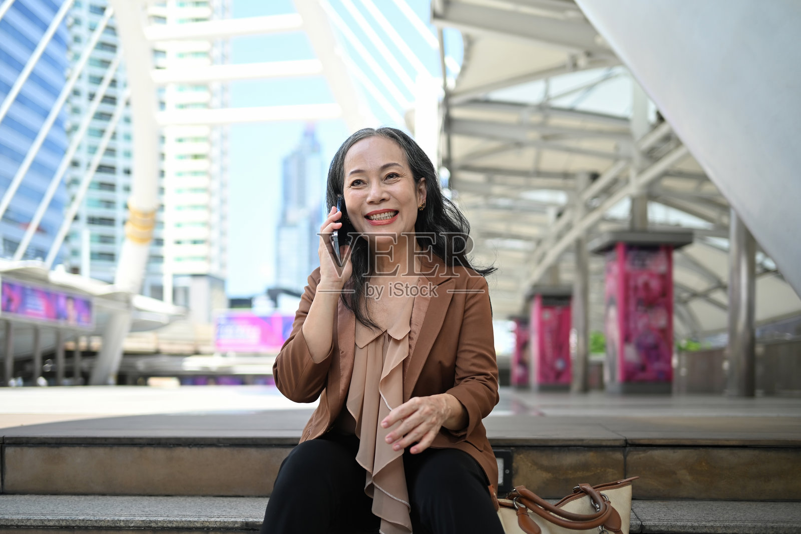 成功的中年女商人在现代城市中享受电话交谈照片摄影图片