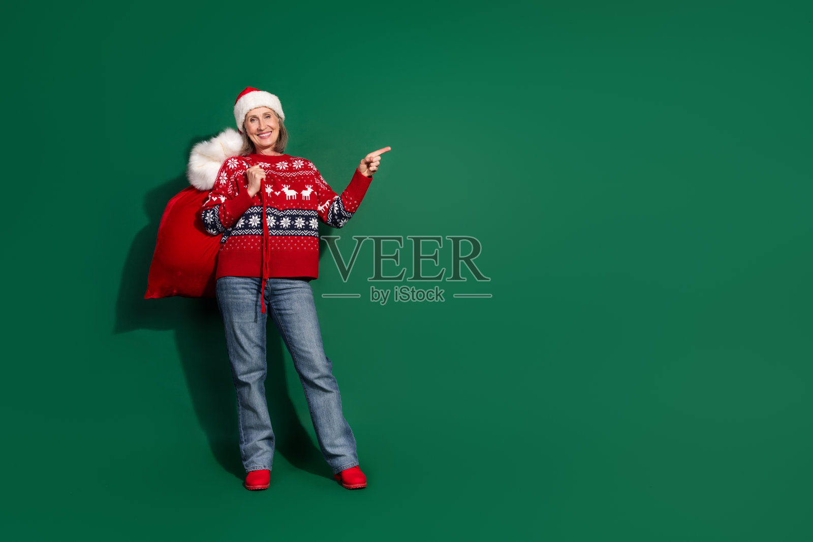 可爱的女孩穿着红色印花衣服，手提礼物袋，背景是绿色的空白空间。照片摄影图片