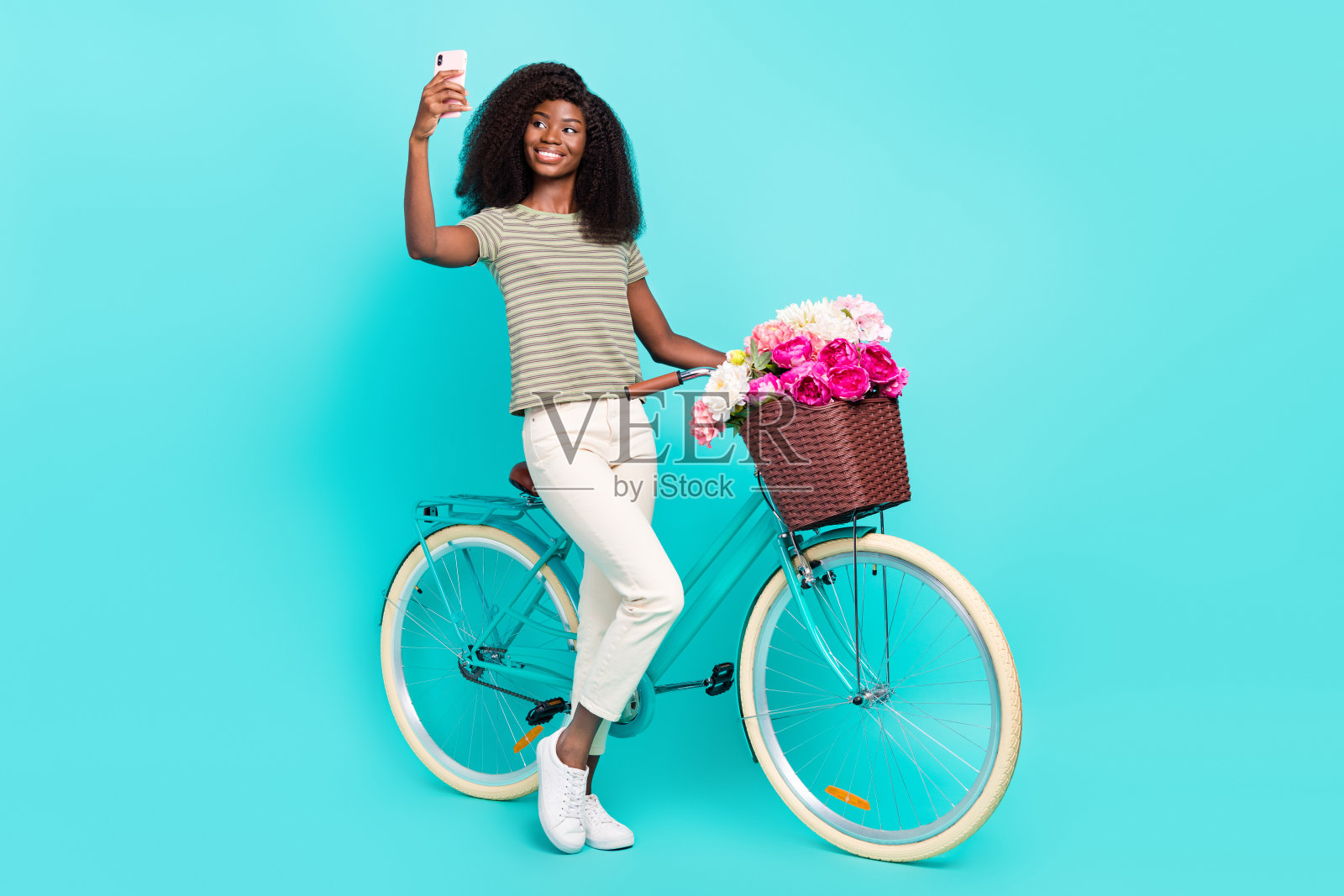 全身照，吸引人的积极人士拿着电话在青色背景下进行自拍视频通话。照片摄影图片