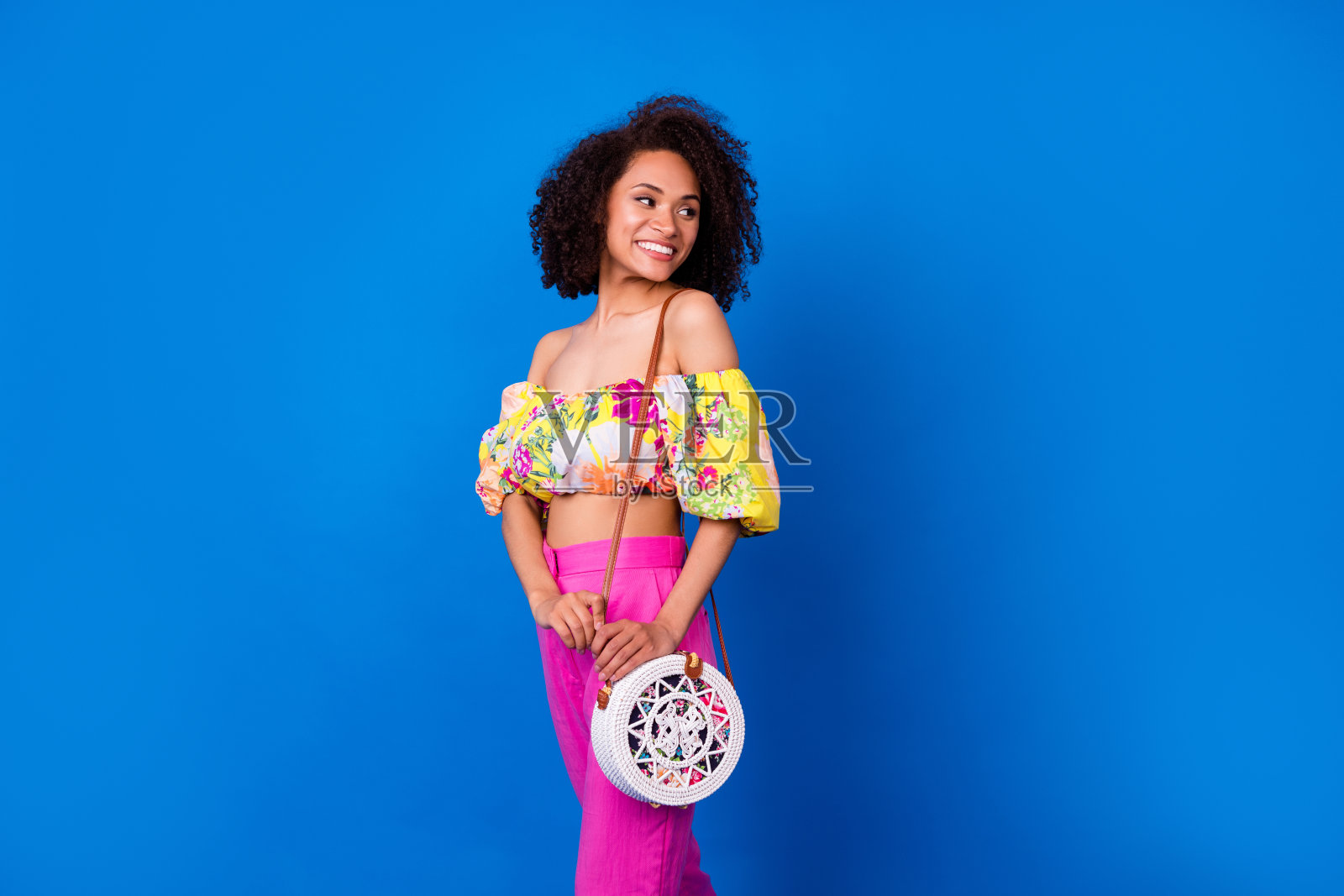 美丽积极的女孩露出灿烂的微笑，面向空旷的空间，展示促销信息，背景为蓝色。照片摄影图片