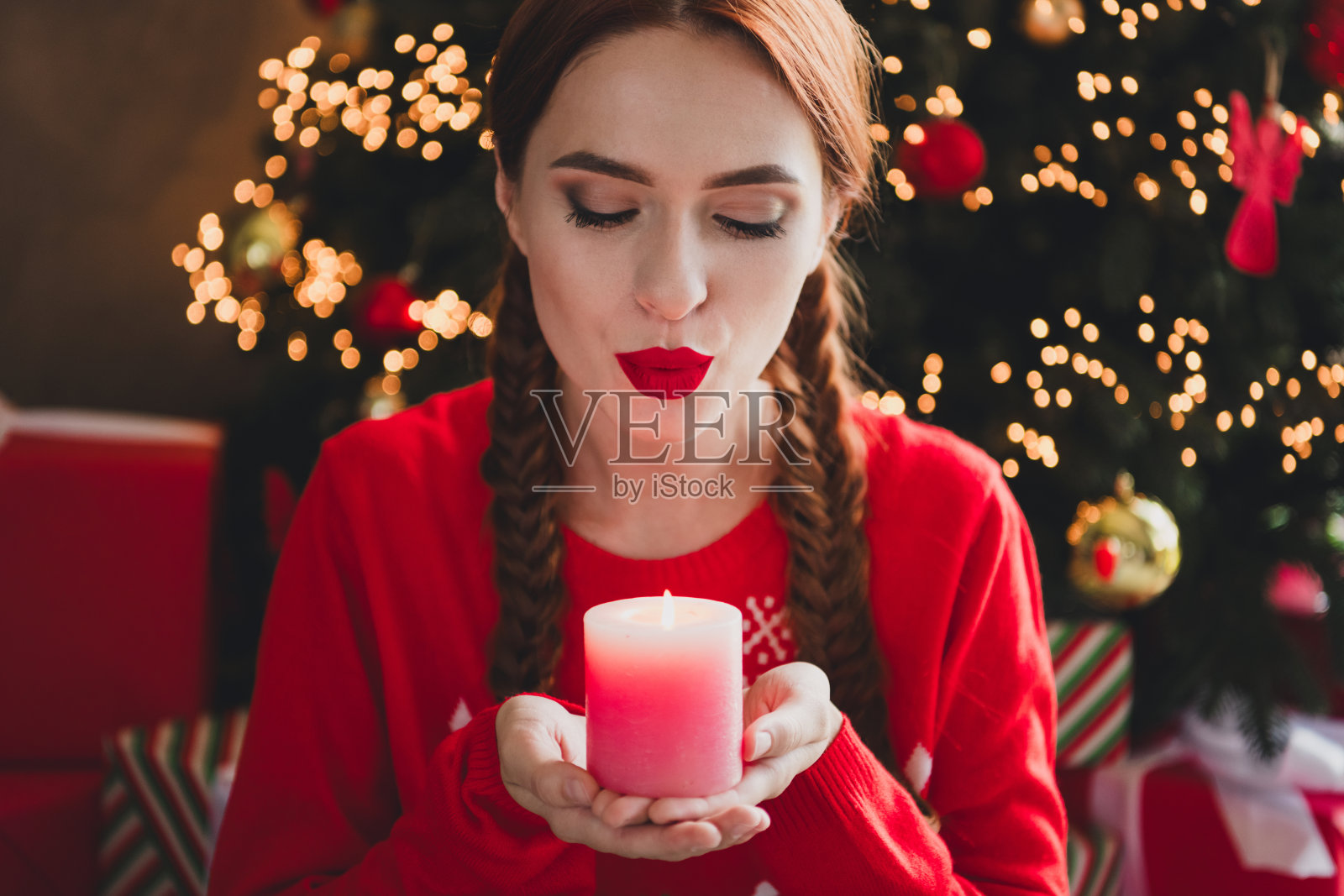 漂亮年轻女孩在公寓室内穿着毛衣，吹灭圣诞节蜡烛的特写照片照片摄影图片