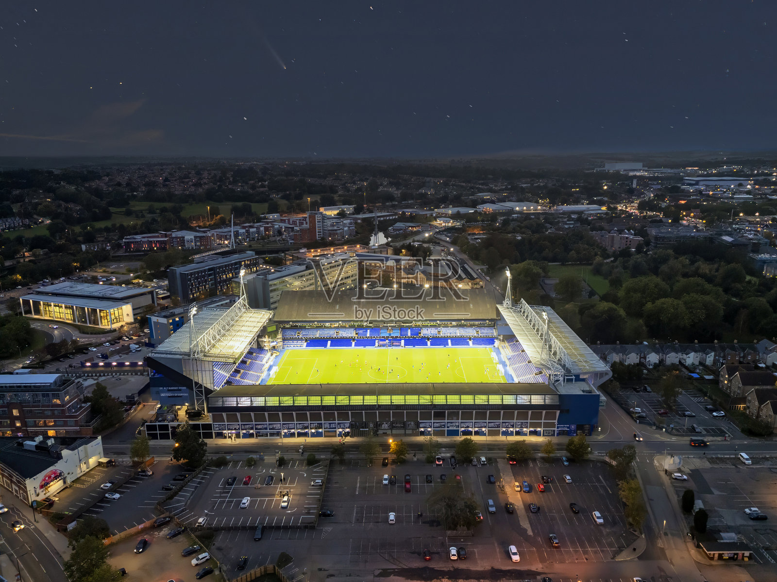 在英国萨福克郡伊普斯威奇的波特曼路上空,夜空中出现了一颗彗星,照亮了洪水灯。照片摄影图片