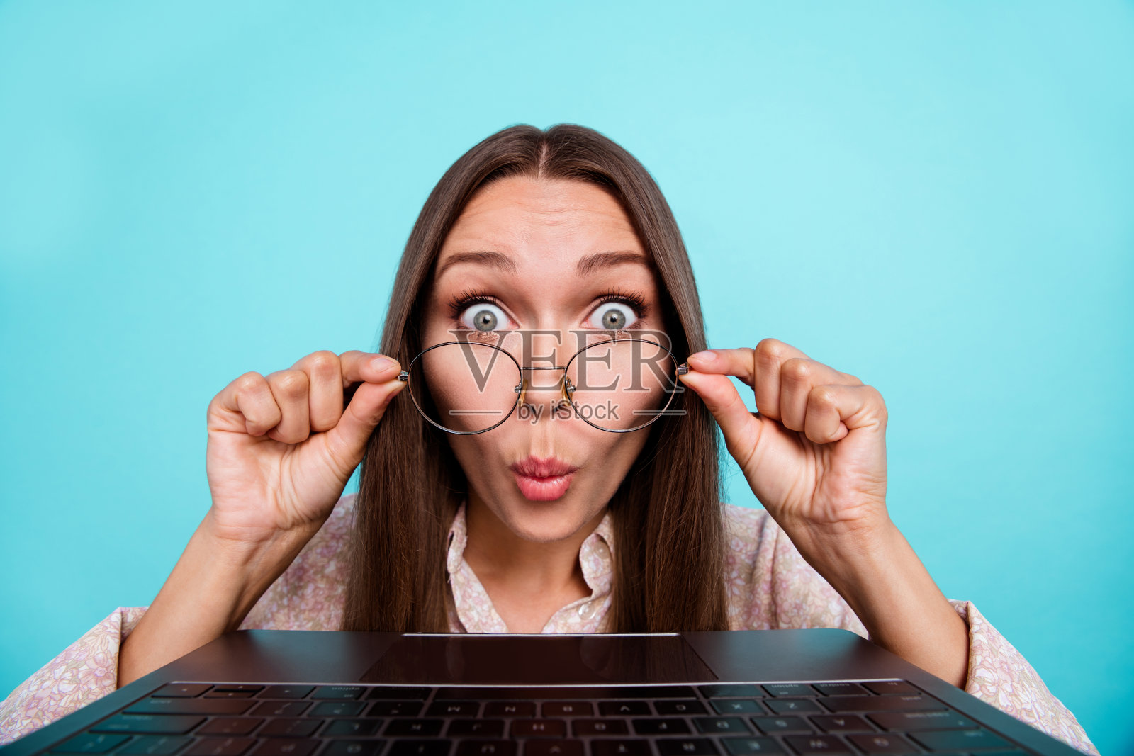 惊讶的女性职业首席执行官经理，看到网络摄像头中的错误，印象深刻，背景为青色。照片摄影图片