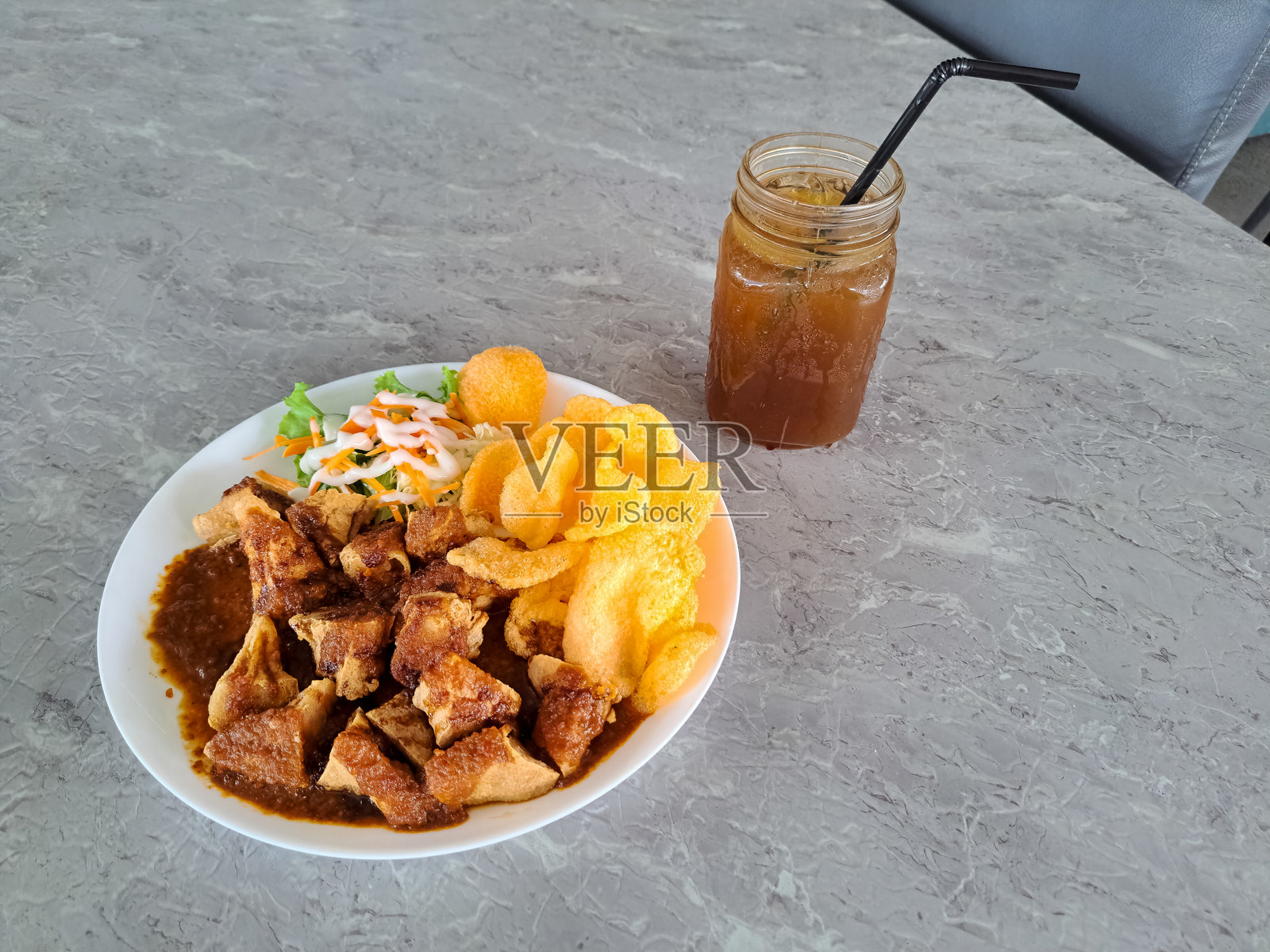 炸豆腐肉丸（Batagor）配上特制的花生酱和酸辣酱，搭配泡菜和脆饼或克鲁普。新鲜的冰茶盛在玻璃杯中。食品和饮料菜单。照片摄影图片