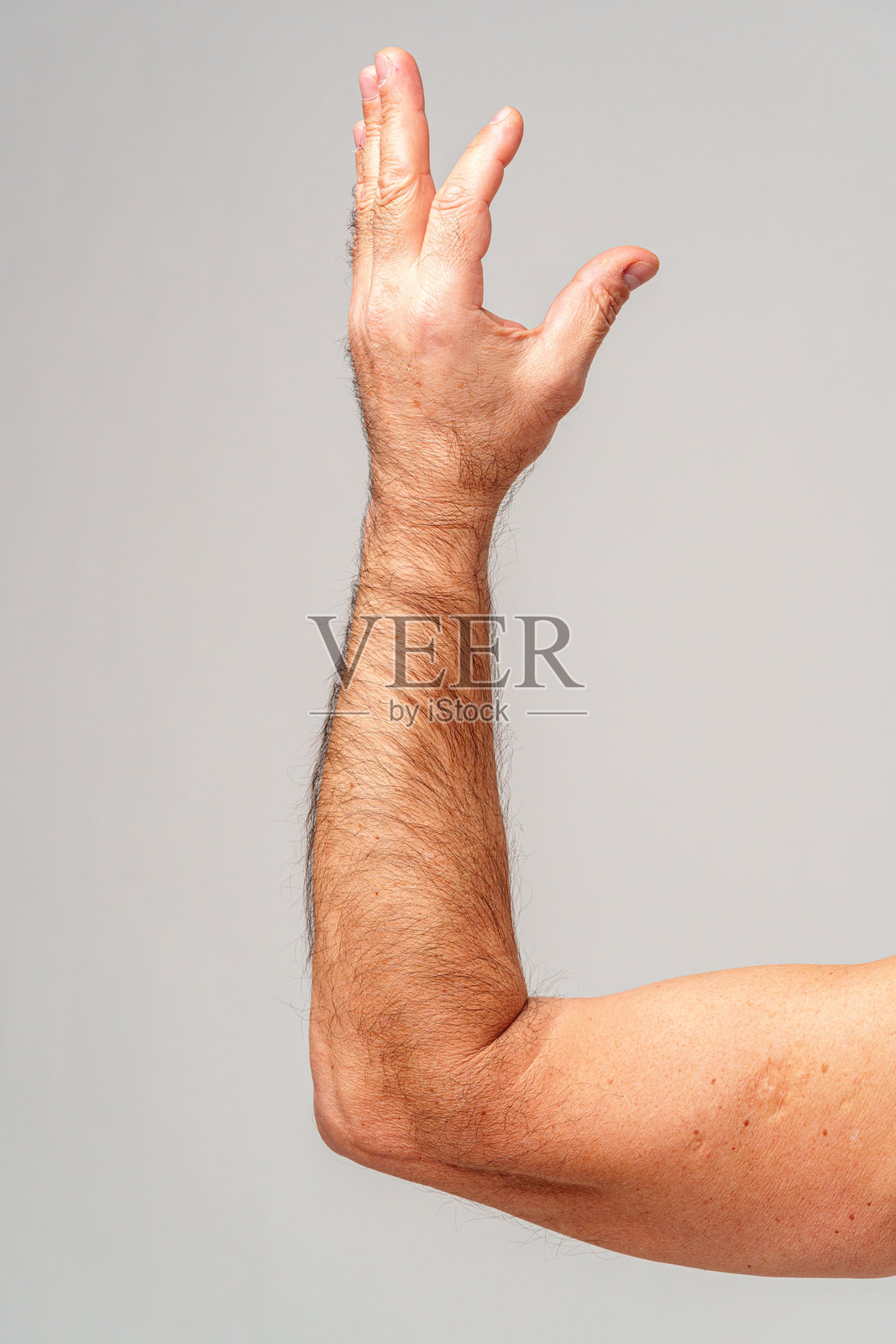 一只举起的手臂，手掌伸出，做出手势，背景为中性色调。照片摄影图片