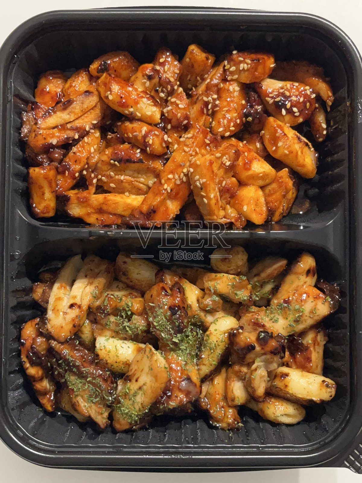 一盒带有特殊韩国调味料的韩国炸鸡。有些鸡块配有辣酱。外脆内嫩，美味可口。照片摄影图片