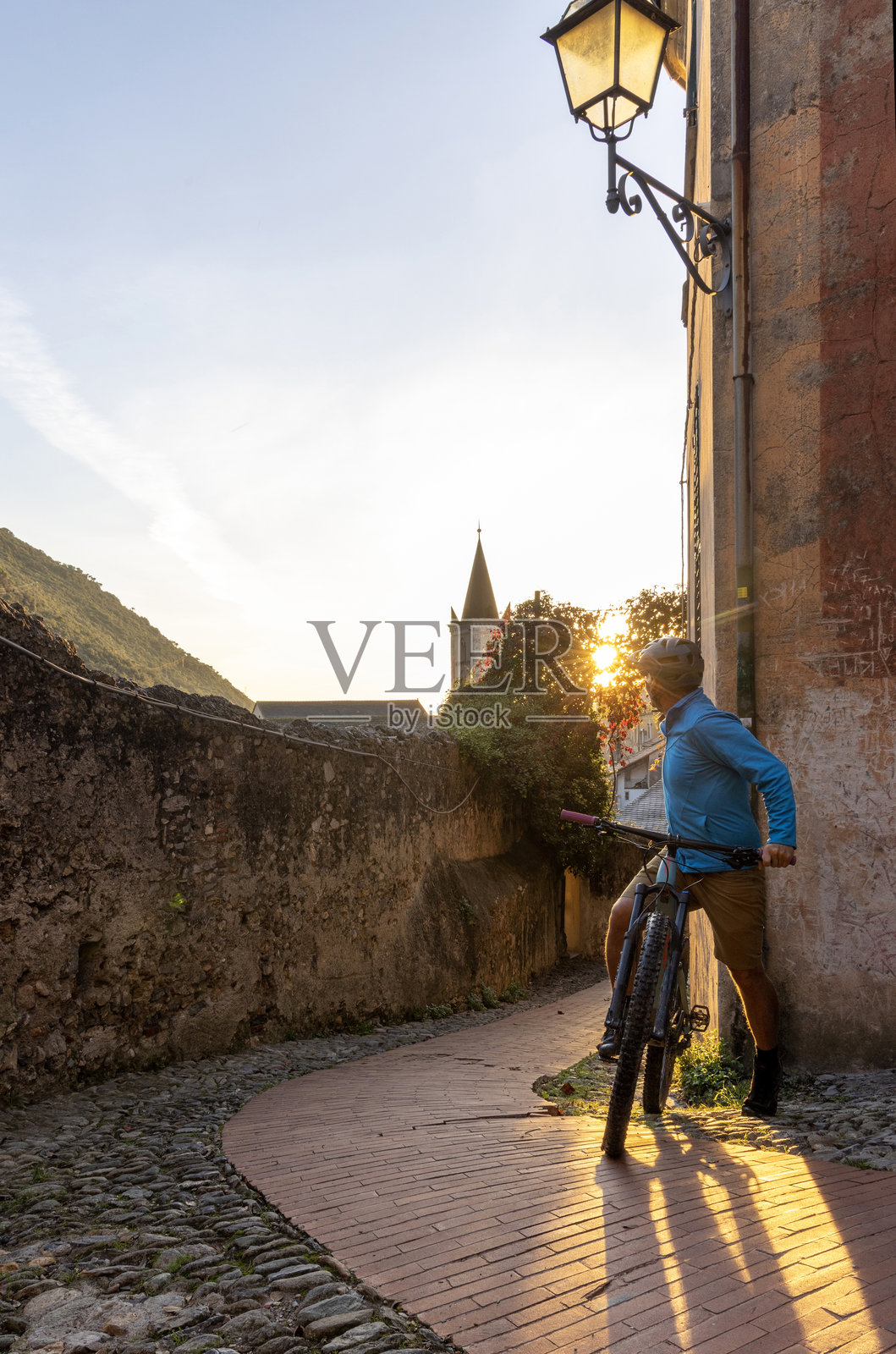 成熟的山地自行车骑士在古老的村庄观看日出照片摄影图片