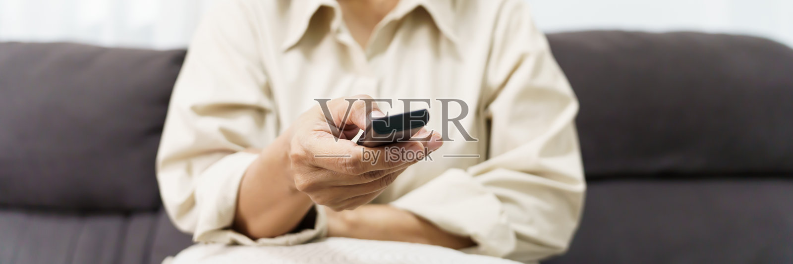 老年女性观看智能电视并使用遥控器 中年亚洲女性在家中享受电影和电视剧的时光照片摄影图片