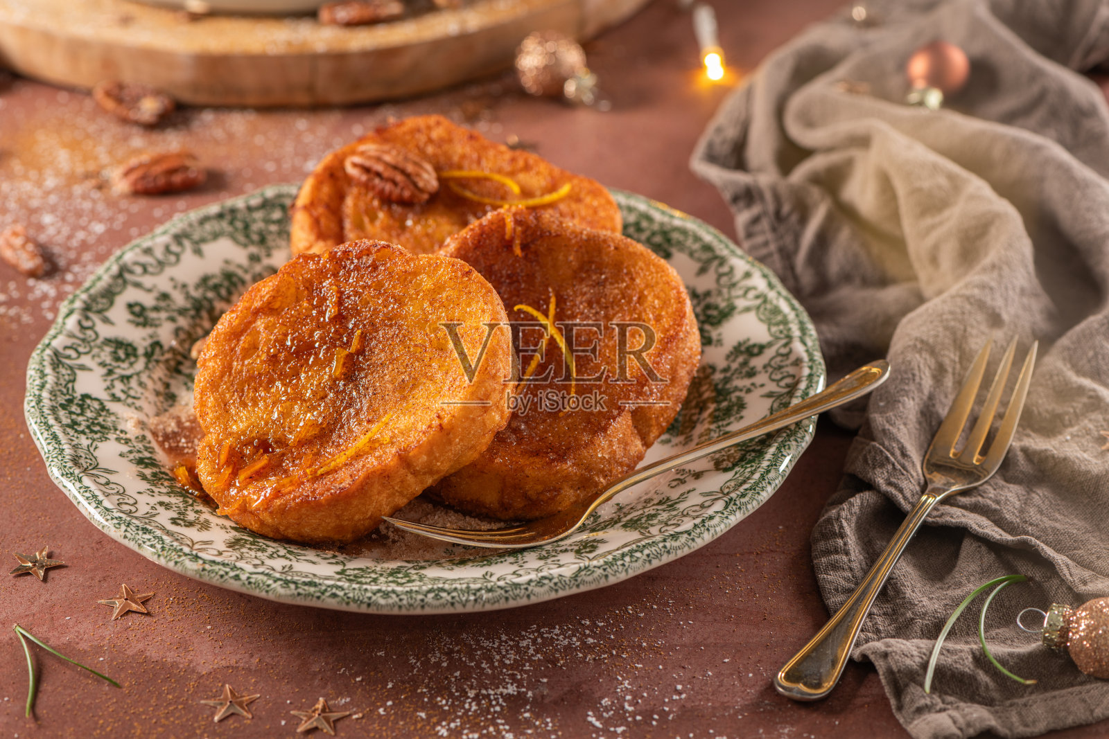 传统圣诞法式吐司或拉巴纳达，配有糖浆、肉桂和胡桃，摆放在圣诞节时的乡村厨房台面上。照片摄影图片