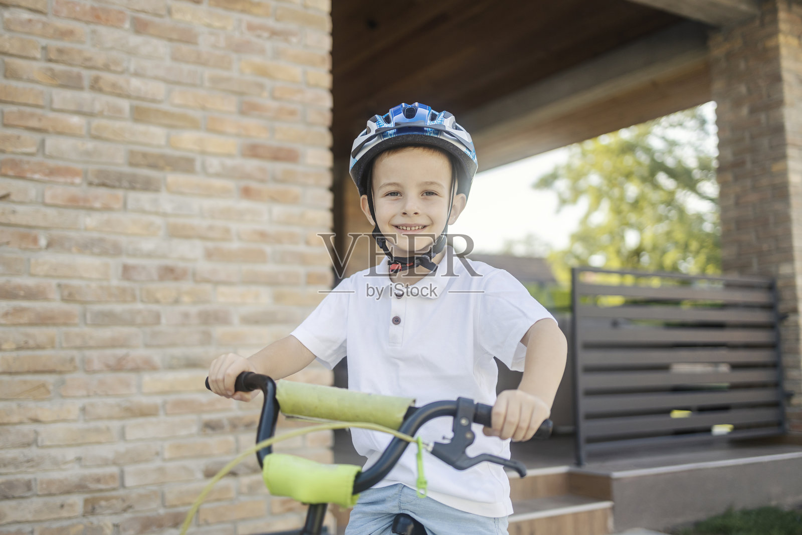 一个年轻男孩坐在自行车上，头戴安全帽，在后院骑行。照片摄影图片
