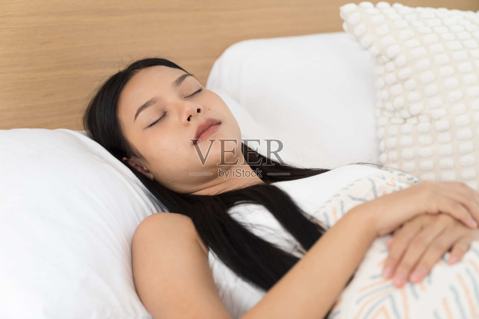 年轻的亚洲女性在卧室的床上睡觉，闭着眼睛，盖着毯子。亚洲女性在早晨卧室的床上睡觉和躺着。健康护理概念照片摄影图片