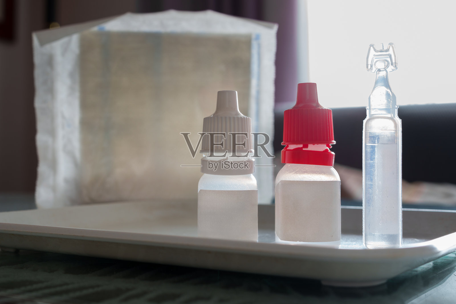 柔和灯光下的托盘上的医用眼药水瓶照片摄影图片