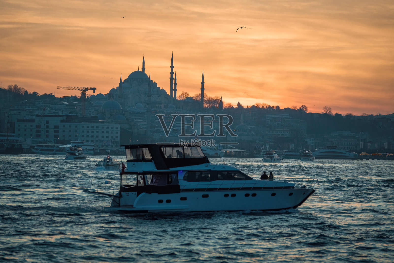 博斯普鲁斯清真寺的美丽日落剪影，水面上有船只，位于土耳其伊斯坦布尔的苏丹艾哈迈德地区。照片摄影图片