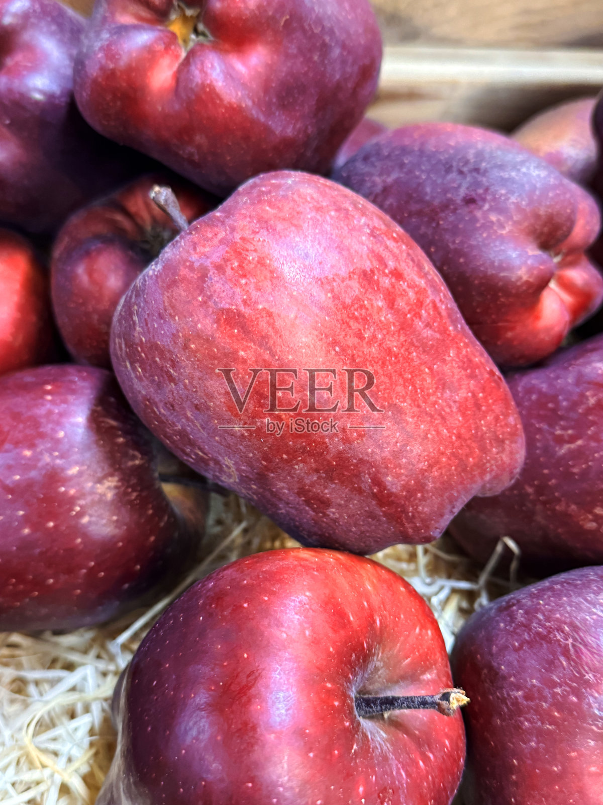 农场商店的产品展示全景，深红色皇家佳苹果（Malus domestica 'Royal Gala'）堆放在木箱中，果实带有果梗，光滑且有斑点的外皮，箱内铺有稻草，俯视角度。照片摄影图片