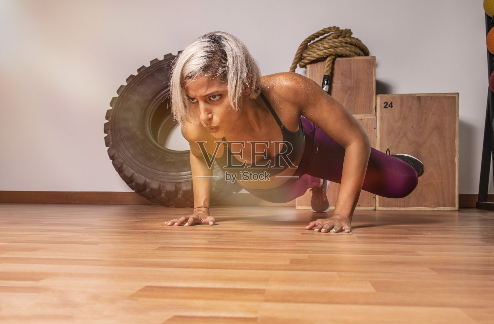年轻女性在健身房的木地板上全身心锻炼照片摄影图片