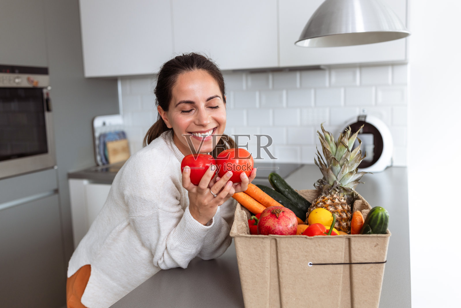 一位女性在享受来自杂货配送箱的新鲜农产品照片摄影图片