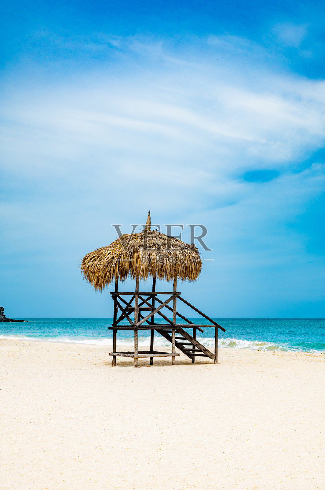 海滩小屋有一个稻草屋顶，坐落在沙滩上照片摄影图片