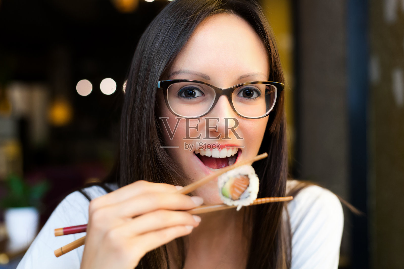 年轻女性在餐厅用筷子吃寿司照片摄影图片