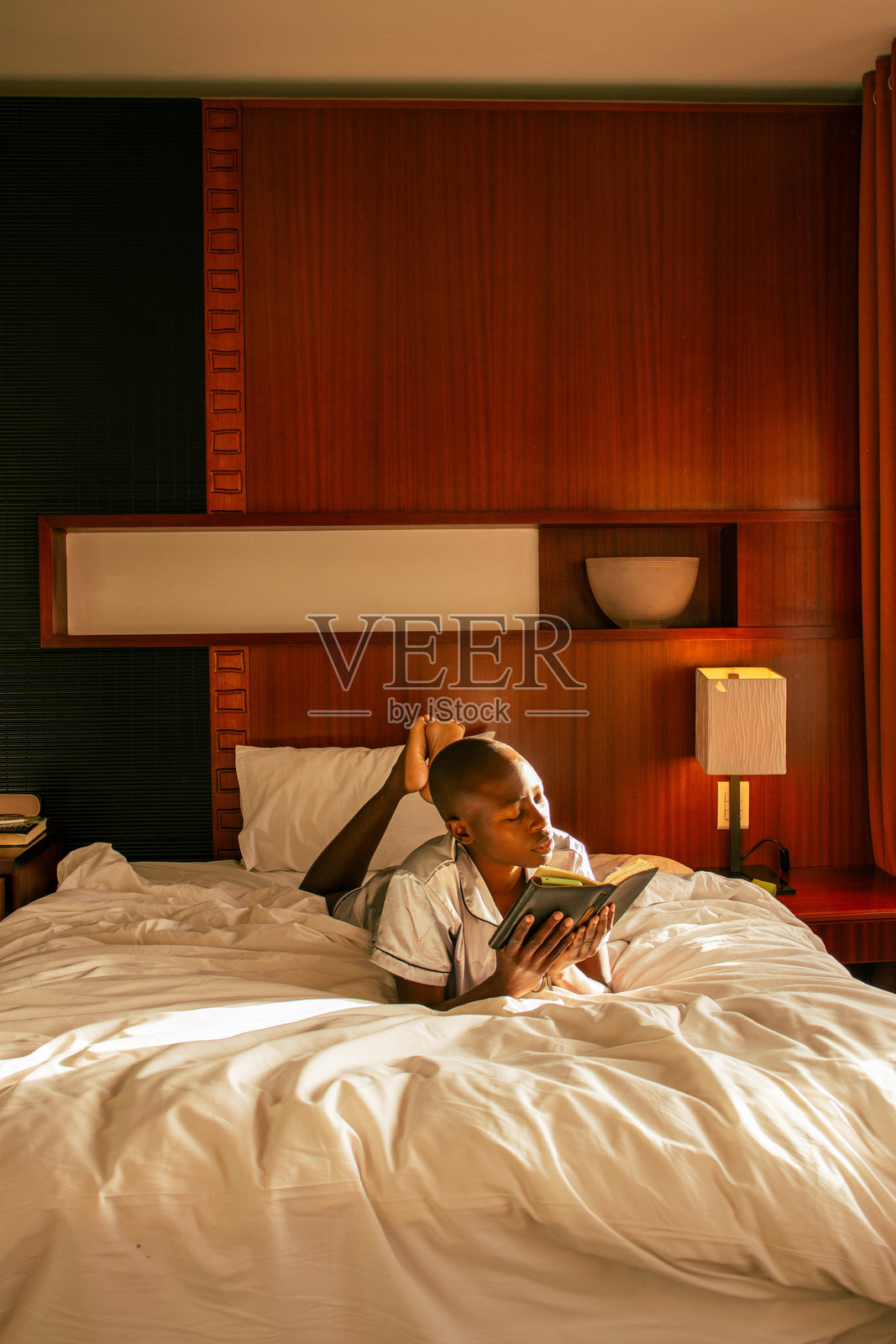 一位年轻的黑人女性在床上阅读一本书照片摄影图片