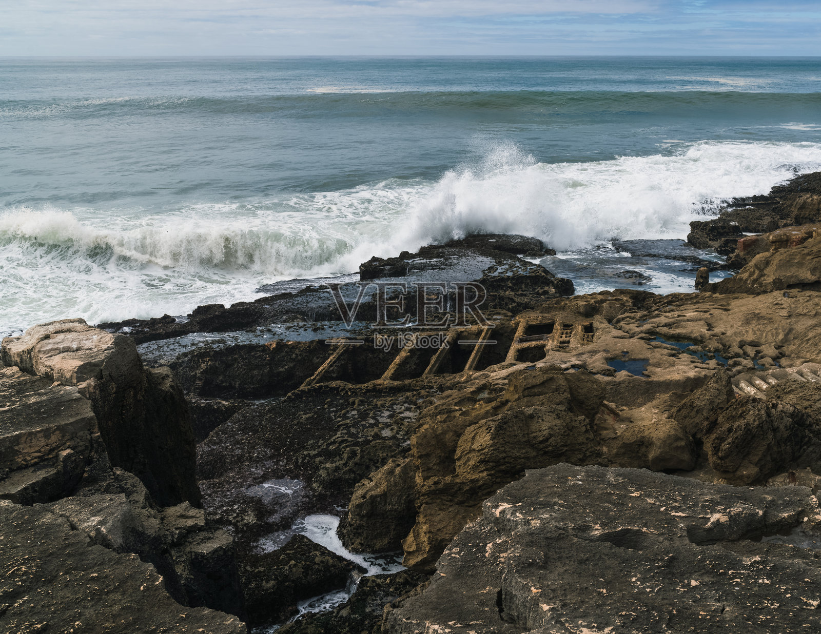 海浪拍打岩石海岸的白色波涛。照片摄影图片