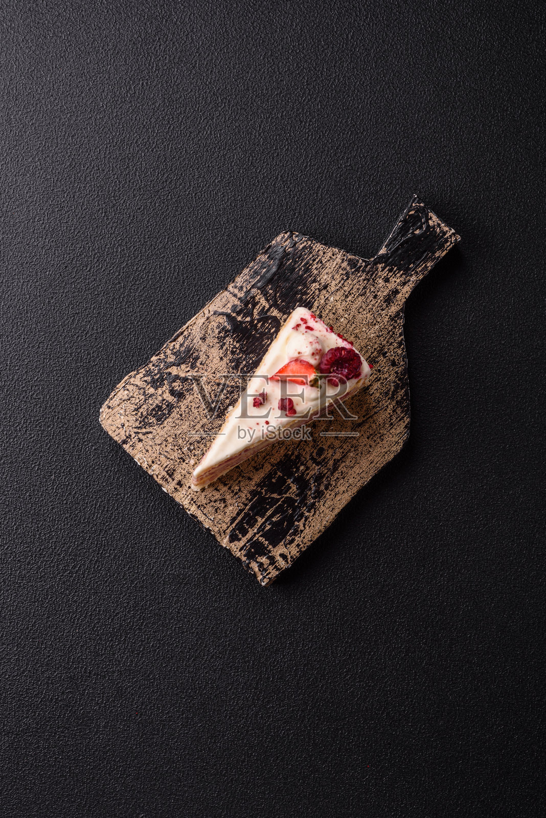 一块夹有白色奶油、覆盆子和草莓的甜层蛋糕照片摄影图片