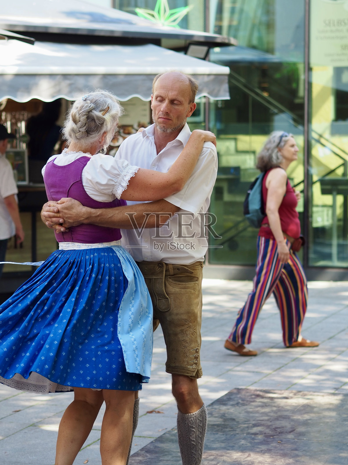 奥地利萨尔茨堡 - 2024年8月31日：一对快乐美丽的情侣身着民族服装，在公园里随着当地乐团演奏的奥地利民族音乐翩翩起舞。照片摄影图片