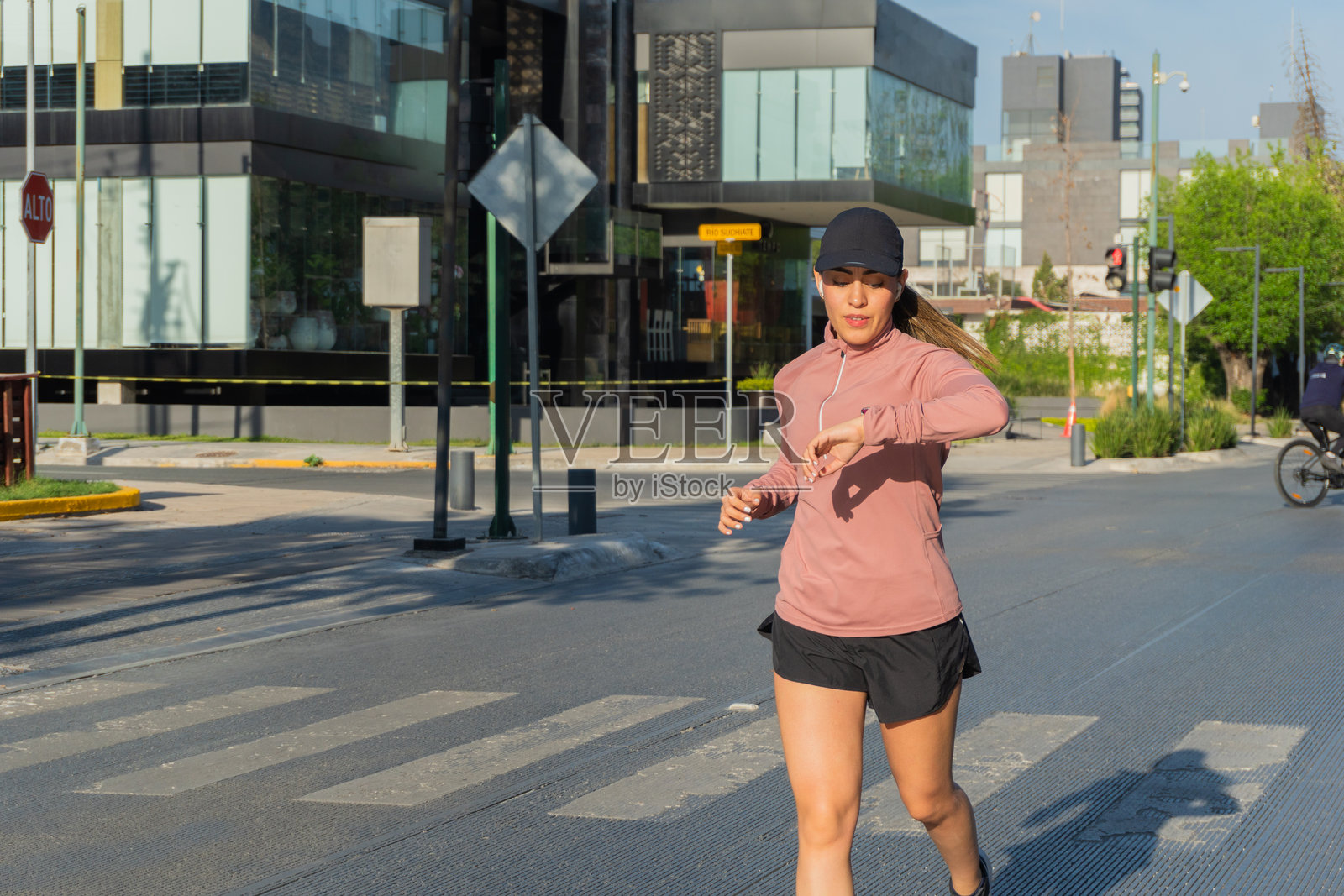 拉丁裔女性在阳光明媚的日子里户外慢跑时查看智能手表照片摄影图片