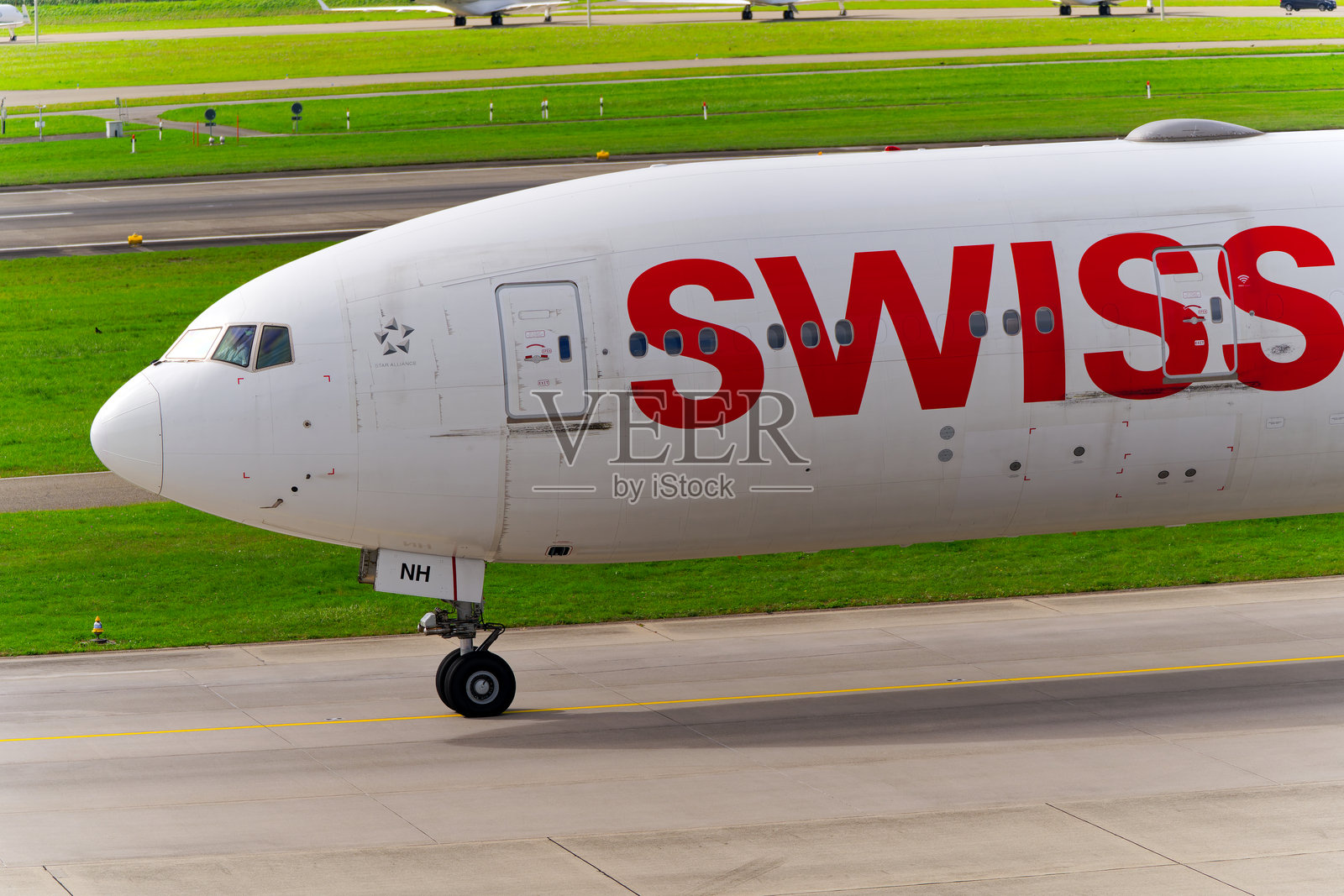 瑞士客机波音777-3DE(ER) HB-JNH在苏黎世克洛滕机场的机头特写，背景是阴云密布的秋日。照片摄影图片