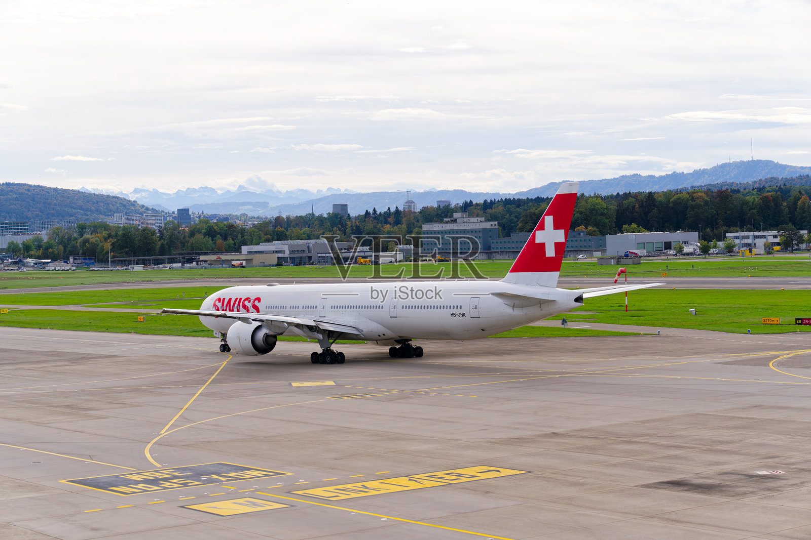 瑞士客机波音777-300(ER) HB-JNK在苏黎世克洛滕机场的阴 cloudy 秋日滑行至跑道。照片摄影图片