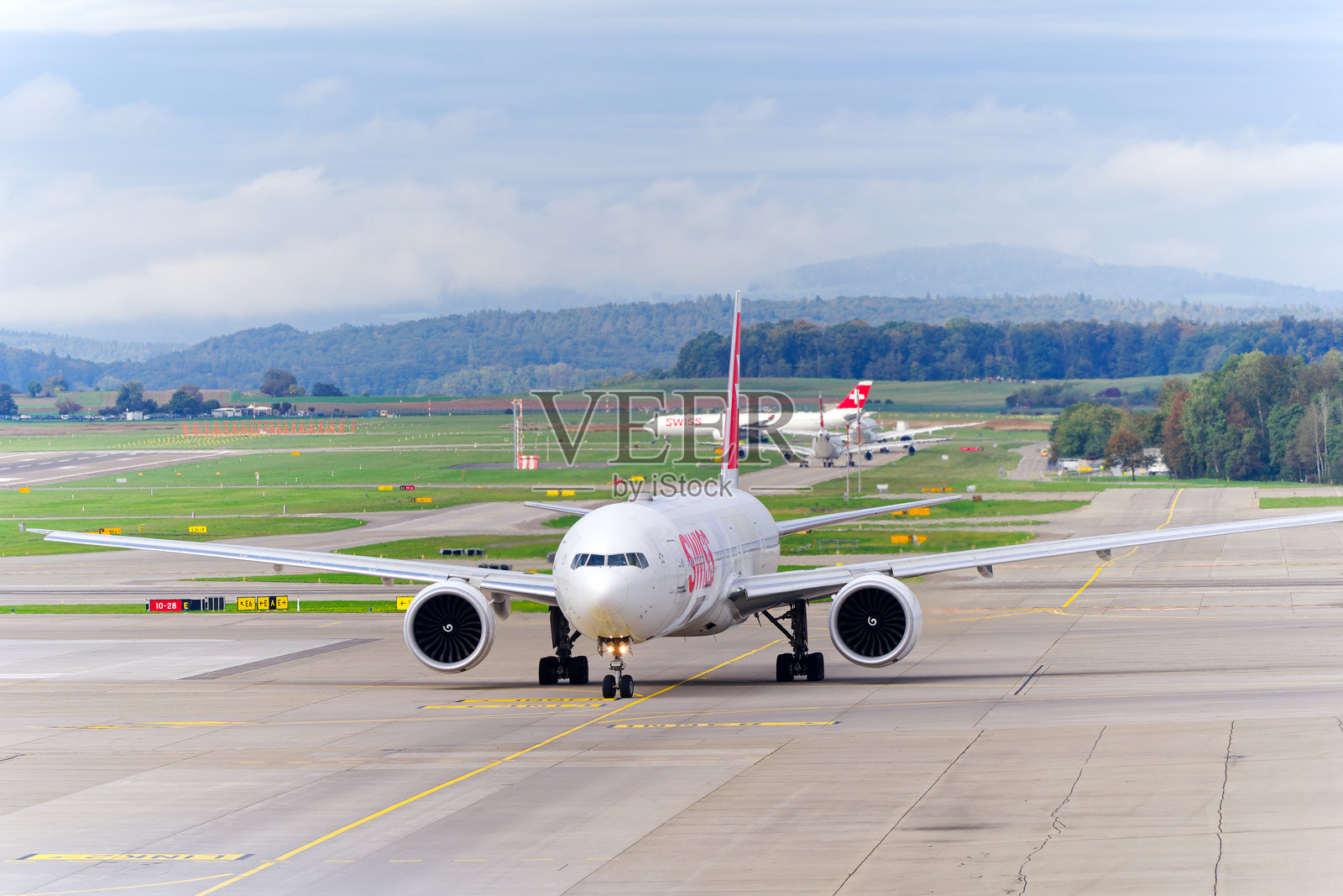 瑞士客机波音777-3DE(ER) HB-JNH在苏黎世克洛滕机场的阴云密布的秋日滑行。照片摄影图片