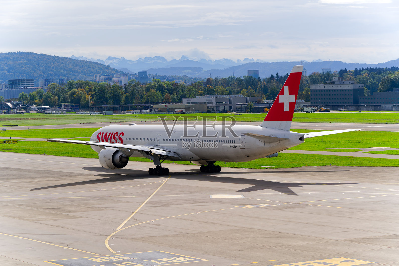 瑞士客机波音777-3DE(ER) HB-JNH在苏黎世克洛滕机场的阴 cloudy 秋日滑行。照片摄影图片
