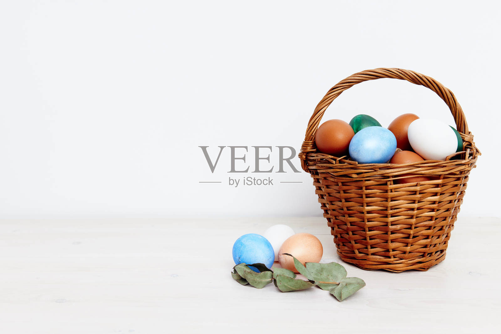 复活节假期，彩色鸡蛋放在篮子里，背景明亮，春季礼物照片摄影图片