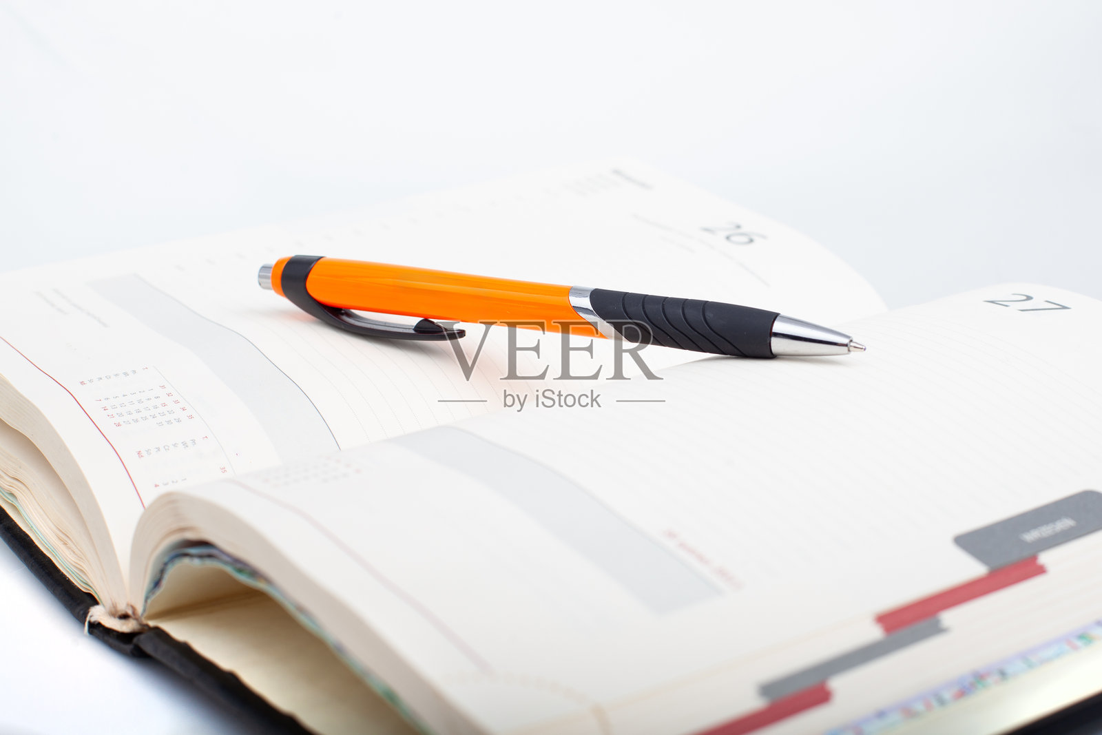 打开的计划本，橙色笔在页面上照片摄影图片